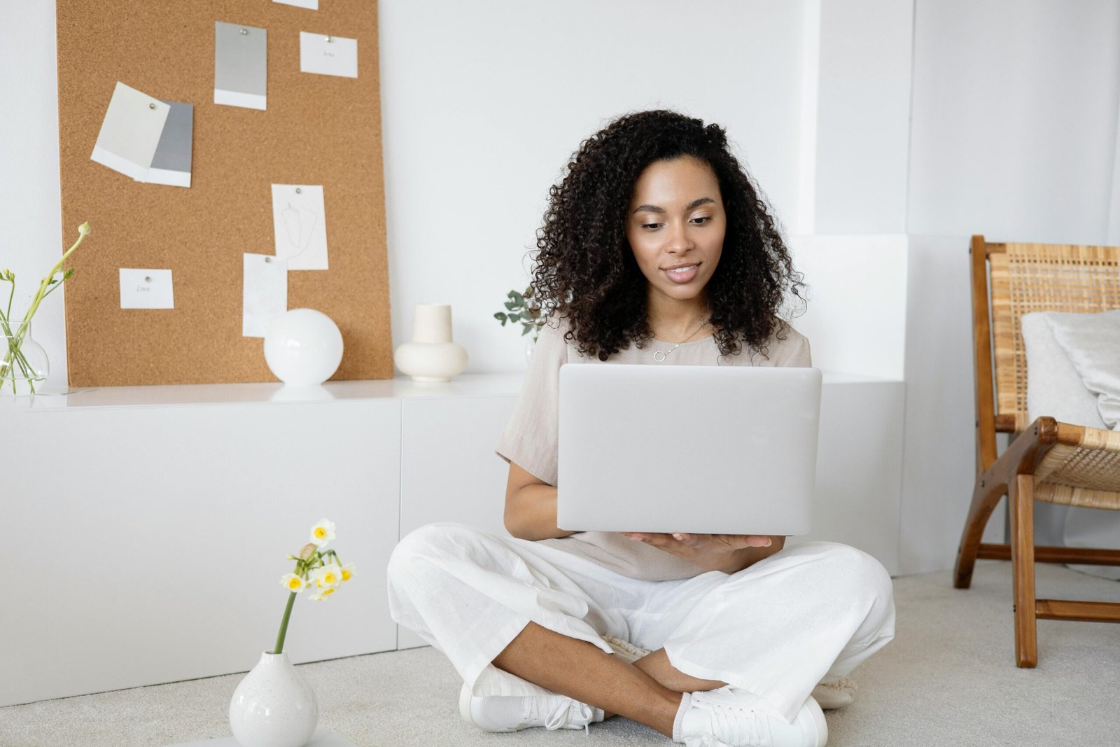 Young woman with curly hair working on her laptop in a cozy home setting, exuding confidence and focus.